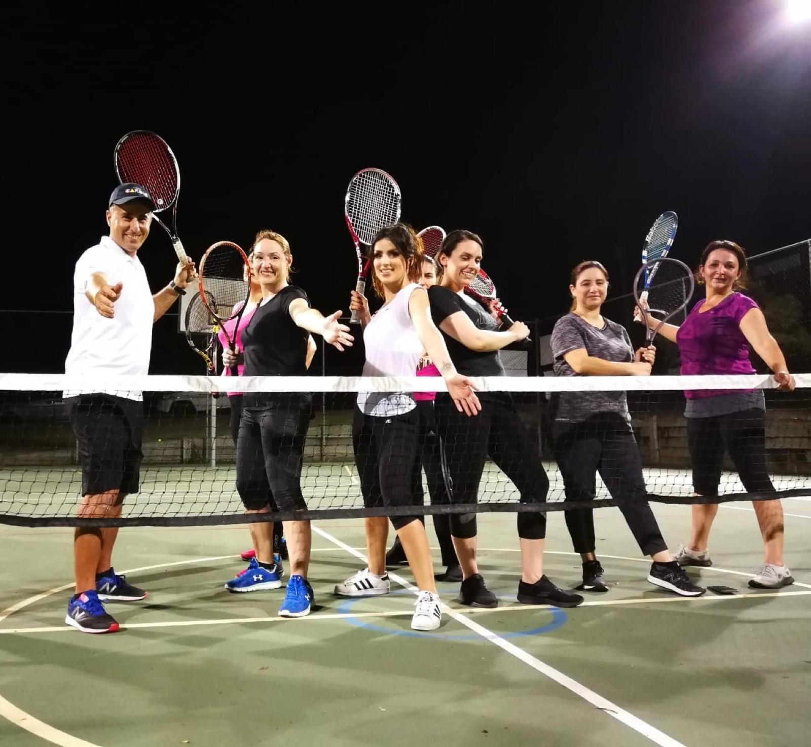 Adult tennis group lesson under lights at a Smart Tennis Academy court in Brisbane